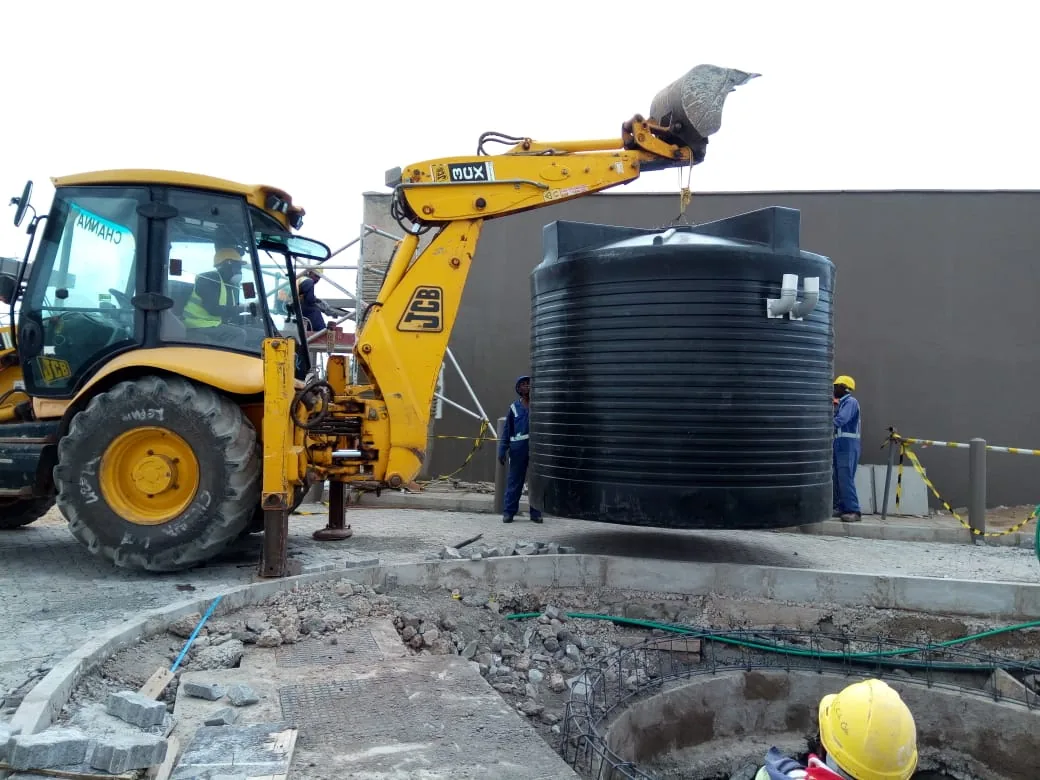Water tank being installed by a backhoe on site