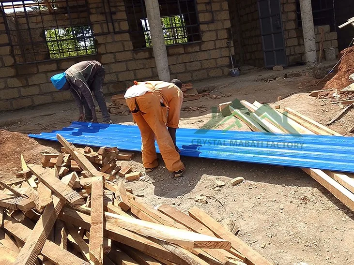 Workers fixing corrugated roofing sheets on timber trusses